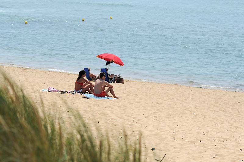 Campeurs avec parasol sur une plage à Oléron proche du camping