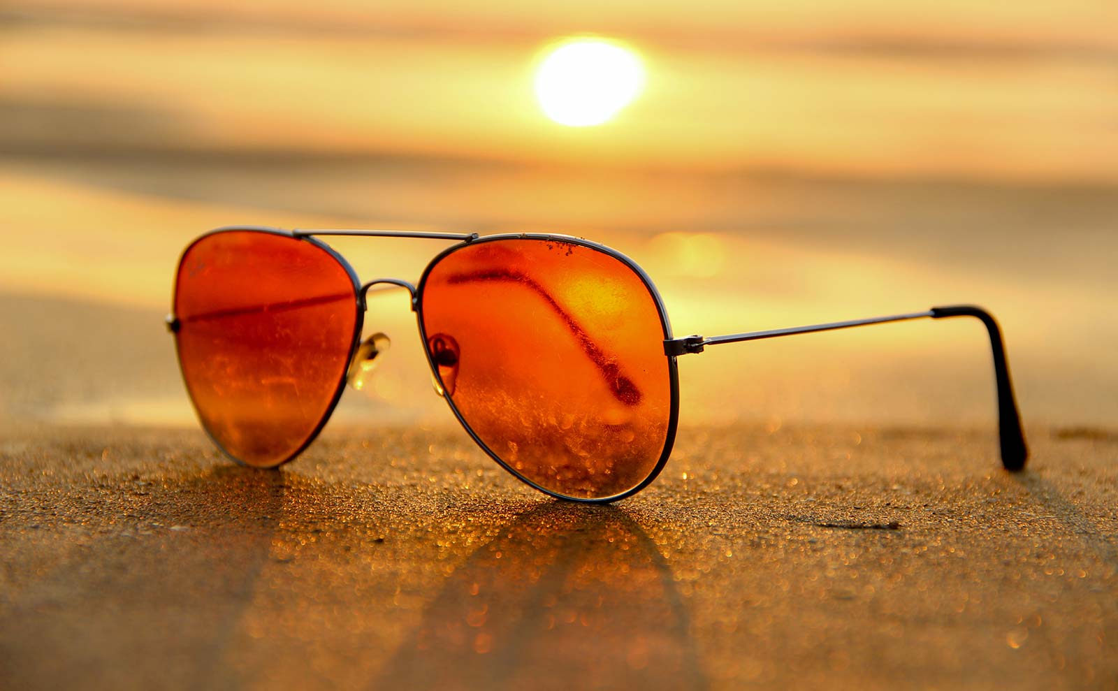 Lunettes de soleil devant un coucher de soleil sur une plage d'Oléron