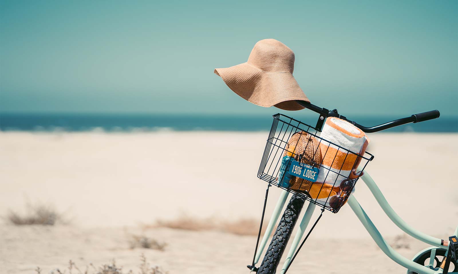 Panier de vélo avec chapeau de paille devant une plage à Oléron