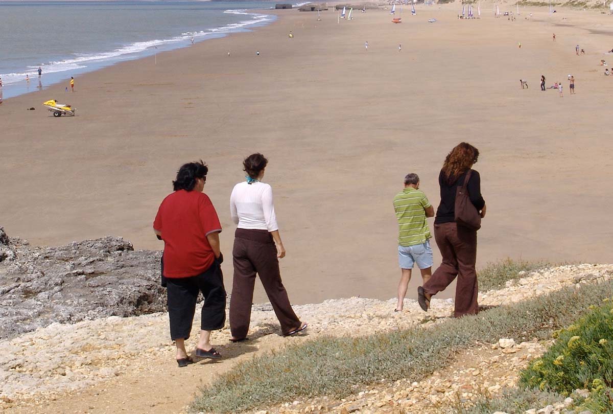 Family of campers descending a dune towards a beach in Oléron