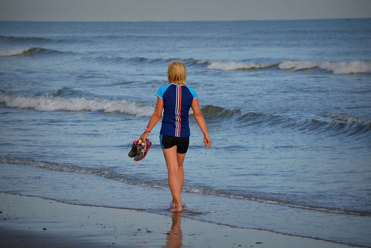 Person walking in wetsuit at the water's edge near Oléron