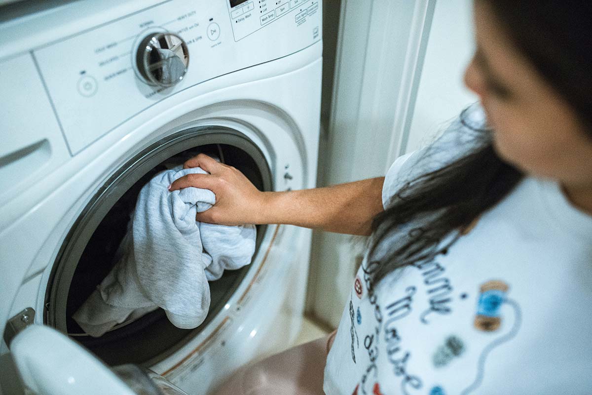 Young woman in front of a washing machine at the campsite laundromat in Oléron